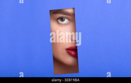 Kreative Collage eines Frauengesichts, gesehen durch einen Ausschnitt in blauem Hintergrund Stockfoto