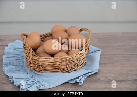 Korb gefüllt mit frischen Hühnereiern auf Holztisch mit textilen natürlichen Bio-Lebensmitteln Bauernfrühstück Konzept niemand Stockfoto