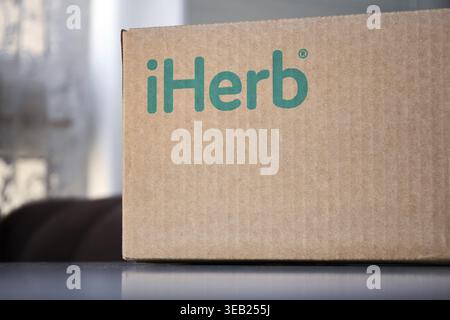 Braune Kartonschachtel mit grüner Logo-Aufschrift iHerb zu Hause, auf dem Tisch. Online-Bestellung, Einkauf, Kauf von Vitaminen und Kosmetika. Empfangen des p Stockfoto