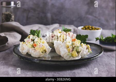 Portionierter Olivier-Salat kreativ auf einem Teller auf dem Tisch serviert Stockfoto