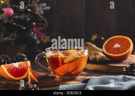 Duftender Tee mit Orangen- und Ingwerstücken in einer Tasse auf dem Tisch Stockfoto