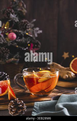Duftender Tee mit Orangen- und Ingwerstücken in einer Tasse auf dem Tisch, vertikale Ansicht Stockfoto