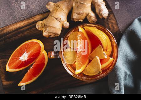 Nahaufnahme von duftendem Tee mit Orangen- und Ingwerstücken in einer Tasse auf dem Tisch Stockfoto