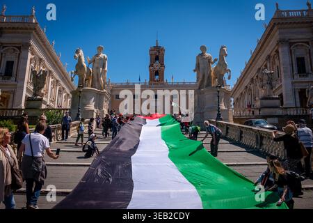 Rom, Rm, Italien. April 2026. Auf der Piazza del Campidoglio fand eine Pressekonferenz statt, um die Bürger darüber zu informieren, dass die erforderlichen Unterschriften gesammelt wurden, um die Gemeindeversammlung zur Abstimmung über die Beendigung der Handelsbeziehungen zwischen kommunalen Unternehmen und israelischen Unternehmen zu ersuchen. Nach der Pressekonferenz entfalten die Teilnehmer die palästinensische Flagge entlang der Stufen, die zum Platz führen. (Kreditbild: © Marco Di Gianvito/ZUMA Press Wire) NUR REDAKTIONELLE VERWENDUNG! Nicht für kommerzielle ZWECKE! Quelle: ZUMA Press, Inc./Alamy Live News Stockfoto