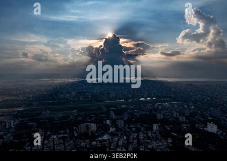 Die Sonne geht über einer Wolkendecke auf und wirft weiche Schatten über Dhaka Stadt in einer ruhigen Drohnenperspektive. Bangladesch Stockfoto