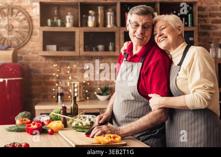 Ältere Frau ihre kochen Mann umarmen in Küche Stockfoto
