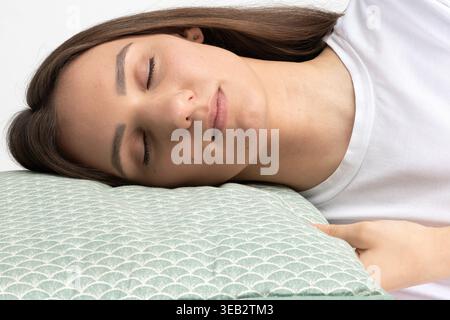 Junge Frau, die mit geschlossenen Augen auf einem weichen, strukturierten Kissen ruht Stockfoto