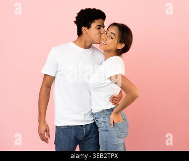 Ein lächelndes Paar, das einen süßen Moment in einem Studio mit pastellrosa Hintergrund teilt Stockfoto