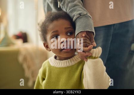 Schwarzes Kind hält Elternhand während finanzieller Härten der Familie Stockfoto