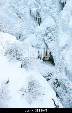 Bergsteiger, die im Winter den steilen gefrorenen Wasserfall erklimmen Stockfoto