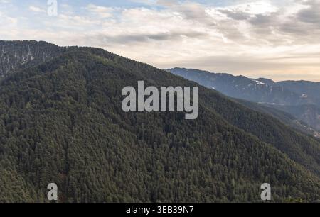Malerische Bergkette mit mehrschichtigen Hügeln und immergrünem Wald unter bewölktem Himmel Stockfoto