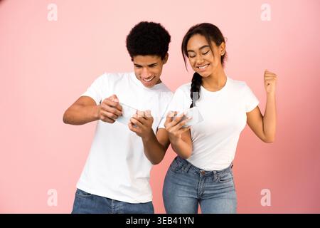 Zwei junge Menschen nehmen an einer Spielaktivität teil, die sich auf ihre Mobilgeräte konzentriert Stockfoto