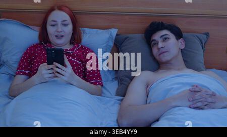 Zwei Personen, die nachts im Bett Mobiltelefone benutzen Stockfoto