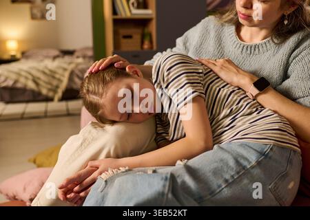 Mutter tröstet krankes Kind, das zu Hause während der Genesung ruht Stockfoto