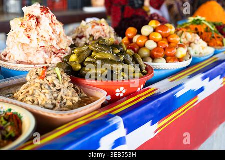 Eingelegtes Gemüse und fermentierte Lebensmittel in Schüsseln auf dem Siab Basar in Samarkand. Farbenfrohe Ikat-Tischdecke und reichlich Produkte aus dem Markt sind ideal für Stockfoto