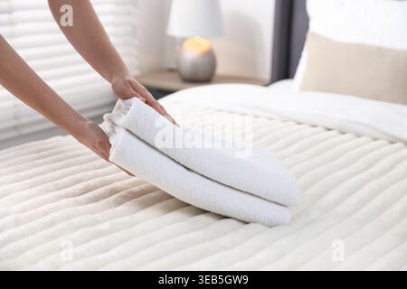 Frau, die Handtücher aus dem Bett nimmt, Nahaufnahme Stockfoto