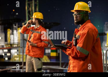 Das Ingenieurteam der Offshore-Plattform für fossile Brennstoffe analysiert die Extraktionseffizienz während des 24-Stunden-Betriebs. afroamerikaner auf dem Bohrkahn und Kollege, der Schiffssysteme konfiguriert Stockfoto