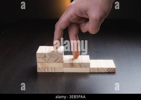 Ziele des Erfolgs und des Geschäftswachstums, dargestellt durch die Hand, die auf eine Holzwürfelleiter klettert. Erfolgskonzept in großen und mittleren Unternehmen. Stockfoto