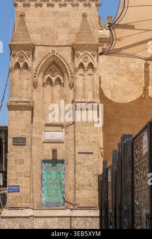 Blick auf die Imam Al-Hussein Moschee mit komplizierten Steinschnitzereien, einer grünen Tür mit arabischer Kalligraphie und einem schwarzen geometrischen Zaun in Kairo, Ego Stockfoto