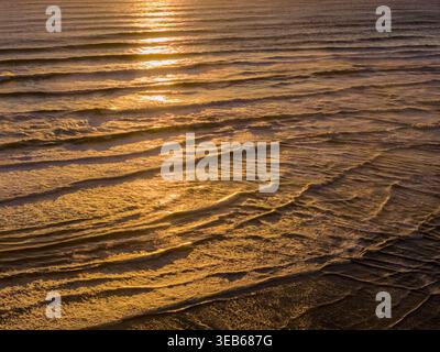 Tasmania Arthur River, der bei Sonnenuntergang am Rande der Welt in den Ozean eindringt - aus der Vogelperspektive über reflektierende Wellen. Stockfoto