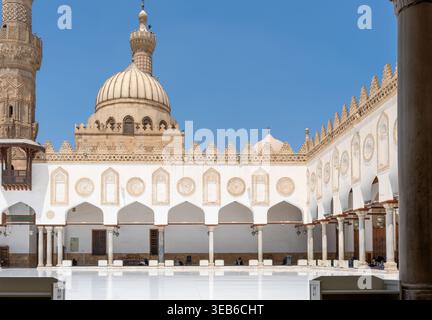 Blick auf den historischen Innenhof der Al-Azhar Moschee mit ihren eleganten weißen Bögen und Steinkuppel unter einem klaren blauen Himmel in Kairo, Ägypten. Stockfoto