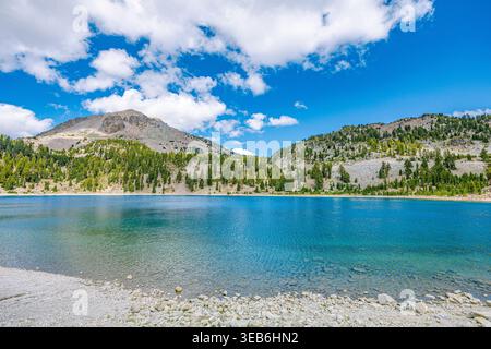 Ein Weitwinkelblick vom felsigen Ufer des Helensees, zeigt das kristallklare Wasser und die umliegenden vulkanischen Hänge von Lassen. Stockfoto