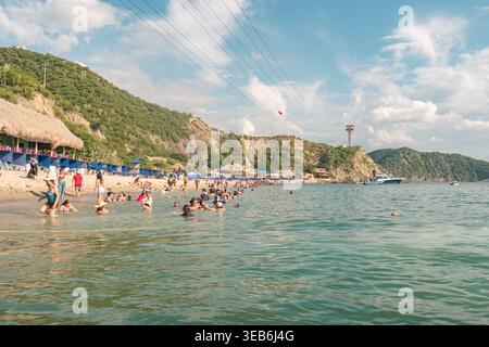 Santa marta, kolumbien - Noviembre 02, 2025 Personen genießen ein erfrischendes Bad im Meer und entspannen am Sandstrand, umgeben von der m Stockfoto