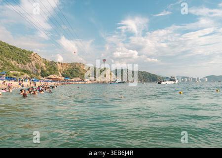 Santa marta, kolumbien - Noviembre 02, 2025 Personen schwimmen und entspannen in klaren karibischen Gewässern vor playa blanca, santa marta, kolumbien, mit mountai Stockfoto