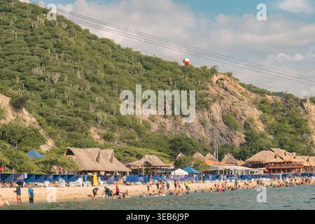 Santa marta, kolumbien - Noviembre 02, 2025 Strandbesucher genießen einen lebhaften tropischen Strand mit einer Person, die über den Berg zieht und adve erfasst Stockfoto