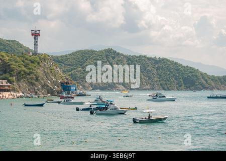 Santa marta, kolumbien - noviembre 02, 2025 Boote füllen eine Küstenbucht in rodadero, santa marta, kolumbien, mit einem Seilrutschturm und grünen Bergen Stockfoto