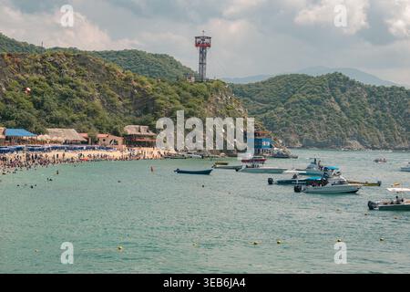 Santa marta, kolumbien - Noviembre 02, 2025 Personen genießen einen geschäftigen Tag am playa blanca, einem beliebten Strand in santa marta, kolumbien, mit Booten im turq Stockfoto