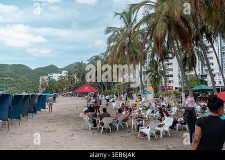 Santa marta, kolumbien - Noviembre 02, 2025 Personen, die sich an einem beliebten Strand in santa marta, kolumbien, mit Hotels, Palmen und Mo Stockfoto