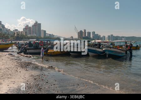Santa marta, kolumbien - Noviembre 02, 2025 Personen genießen den sonnigen rodadero Strand in santa marta, kolumbien, mit Fischerbooten und Motorbooten gesäumt Stockfoto