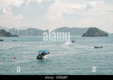 Santa marta, kolumbien - Noviembre 02, 2025 Touristenboote mit Passagieren in der Bucht von rodadero, mit der Stadtlandschaft von santa marta und einer natürlichen Insel darunter Stockfoto