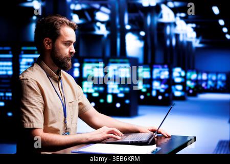 Computerwissenschaftler, die Laptop zum Patchen von Servern verwenden und Unternehmen dabei helfen, Datenbanken zu verwalten, Websites zu hosten und Dateien zu speichern. Cloud-Computing-Manager für Supercomputer im Rechenzentrum Stockfoto