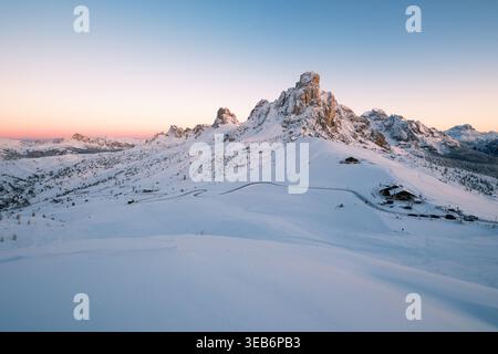 Blick auf schneebedeckte Berggipfel und eine gewundene Straße bei Sonnenuntergang in den Dolomiten, Trentino-Südtirol, Italien. Stockfoto