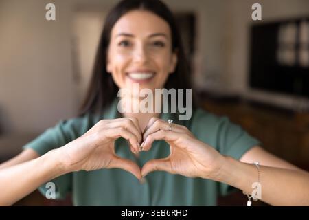 Frau macht Herzgeste mit Händen zu Hause, Nahaufnahme Stockfoto