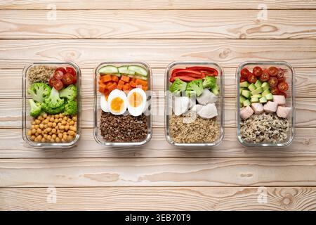 Gesunde Mahlzeit Vorbereitungsboxen mit Lachshähncheneiern und veganen Kichererbsenschalen auf hölzernem Hintergrund Stockfoto