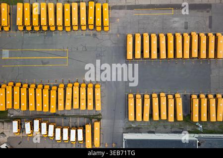 Gelbe Schulbusse parkten in einem organisierten Muster auf einem großen Asphaltparkplatz Stockfoto