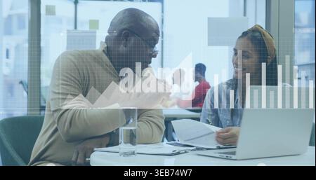 Ich überprüfe Laptop, Frau in Jeansshirt mit Stirnband und Seniorenmann in beigem Pullover im Büro Stockfoto