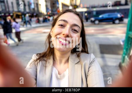 Eine junge Frau lächelt und macht ein Selfie in manhattan Stockfoto