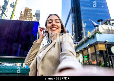 Eine junge Geschäftsfrau lächelt beim städtischen Selfie in manhattan Stockfoto