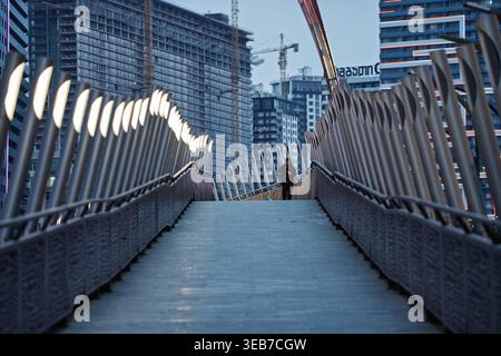 Batumi, georgia 21. april 2026: Person, die über die beleuchtete Fußgängerbrücke in batumi, georgia, mit städtischer Architektur und Bau VI Stockfoto