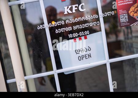 Batumi, georgia 21. april 2026: kfc-Schaufensterfenster in batumi mit zweisprachigem geöffnetem Schild und Öffnungszeiten auf georgisch und englisch, städtische Straße r Stockfoto
