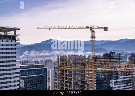 Batumi, georgia 21. april 2026: turmkräne bauen moderne Hochhäuser in batumi, georgia, mit malerischem Blick auf ferne Berge unter ihnen Stockfoto