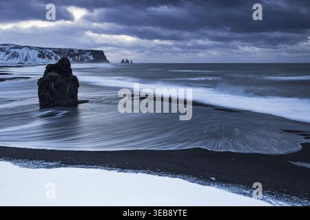 Blick auf den schwarzen Sandstrand und das Meer unter einem stimmungsvollen Winterhimmel in Vik, Myrdalshreppur, Island. Stockfoto