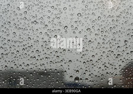 Regentropfen auf dem Fenster mit verschwommenem Stadthintergrund Stockfoto