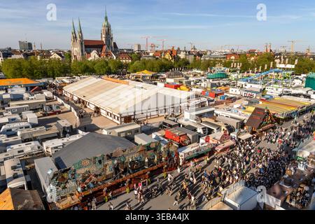 60. Münchner Frühlingsfest, Überblick vom Riesenrad bis zum Horizont, schönstes Frühlingswetter am Wochenende, München, April 2026 Deutschland, München, April 2026, 60. Münchner Frühlingsfest, Blick vom Riesenrad bis zum Horizont mit Kirche St. Paul und Frauenkirche, schönstes Frühlingswetter am Wochenende, Freitag um 18 Uhr, das Abendlicht wirft lange Schatten, Sonne und Temperaturen bis 20 Grad, blauer Himmel, das traditionelle Volksfest findet zum Jubiläum diesmal erstmals für drei Wochen statt, vom 17.04. bis zum 10.05.2026, das erste Frühlingsfest war 1965, Theresienwiese, blauer bayeris Stockfoto