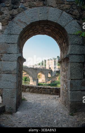 Blick auf die mittelalterliche San Martin-Brücke (Puente de San Martin), eingerahmt durch einen Steinbogen in Toledo, Spanien. Historische Steinbrücke über den Tejo Ri Stockfoto