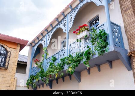Ein traditioneller und historischer Holzbalkon in Blau, dekoriert mit Blumenbeeten. Konzept: Gemütliche Häuser und Straßen in einem Kurort Stockfoto